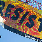 In this image from 2017, Greenpeace activists deploy a banner on a construction crane near the White House reading "RESIST" on Donald Trump's fifth day in office in his first term.