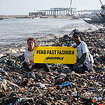 The fashion industry has a massive plastic problem that it outsources to countries in the Global South, where textile waste pollutes the environment. Ghana is one of the world's largest consumers of second-hand textiles. A good 120,000 tonnes of second-hand clothing from Asia, North America and Europe end up in the West African country every year. More than half of the clothing is inferior disposable goods with no resale value - much of it is made of plastic.

On a research trip to Accra, a team from Greenpeace Africa and Greenpeace Germany used infrared scanners to examine discarded clothing at landfill sites and identify the various fibres. The result: almost nine out of ten items of clothing (89 per cent) contain synthetic fibres made from fossil fuels. After the garments are thrown away, these synthetic fibres decompose into microplastics. In the tested clothing from the Kantamanto market - the largest second-hand textile market in West Africa - the figure is as high as 96 per cent.

Greenpeace also analysed the air quality in three wash houses in Accra where textile waste is incinerated. The results show that the air is heavily polluted with hazardous chemicals, many of which are single or multiple carcinogens, mutagens and toxic to reproduction. 

As part of a return-to-sender campaign, Greenpeace shipped textile waste back to Germany in a container designed by Ghanaian artists in order to take further samples and raise awareness about the destructive side of fast fashion. 

Overconsumption in the textile industry and the massive use of synthetic plastic fibres and blended fabrics are causing devastating environmental damage and threatening nature and people in the Global South.

In the picture: Greenpeace banner at Jamestown, a fishery town in Accra where textile waste is washed into the sea