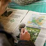 Guests attending Installation First Genetic Free Zone in the Netherlands. The informal meeting is an initiative of a small group of worried citizens and is held in the farm of Robert Koekoek, one of the initiators. One of the guests reads an article about the initiative in the newspaper.