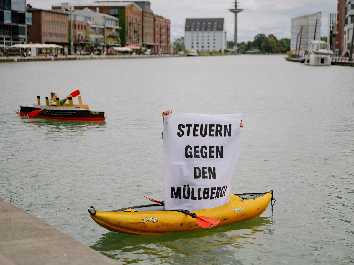 Greenpeace activists stage an impressive image for more environmental protection. A kayak disguised as a Titanic heads straight for an iceberg of packaging waste around three meters high in the harbour basin of Muenster. The scene is accompanied by activists on stand-up paddleboards with banners. The action is part of a campaign for a municipal packaging tax and is intended to send a strong signal for more environmental and resource protection. © Aliona Kardash / Greenpeace