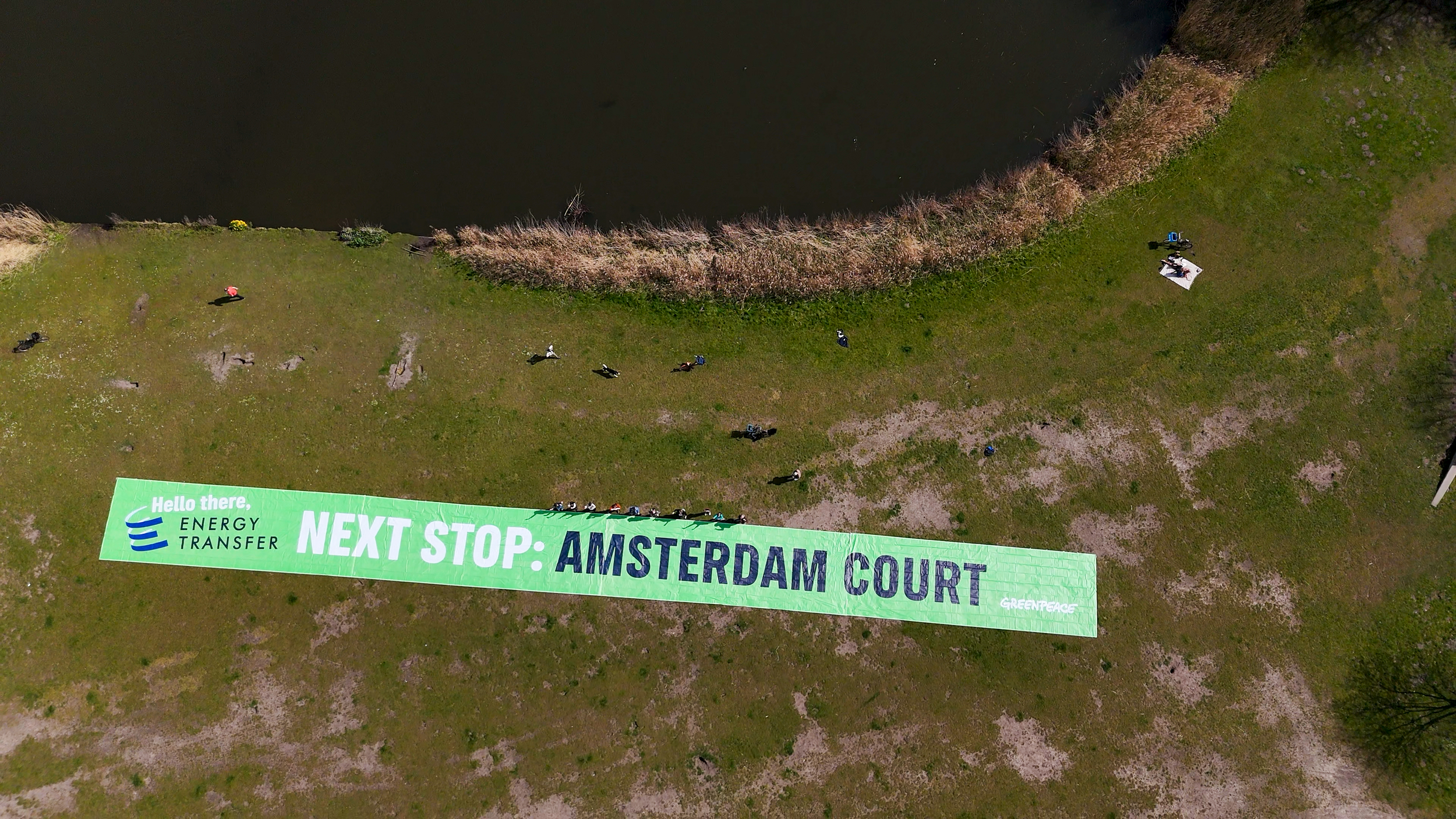 People in Rembrandtpark, Amsterdam display a banner reading 'Hello there, Energy Transfer, next stop: Amsterdam Court', ahead of a hearing on 16 April for the Greenpeace International anti-SLAPP (Strategic lawsuits against public participation) case in the Dutch capital against oil pipeline Energy Transfer.