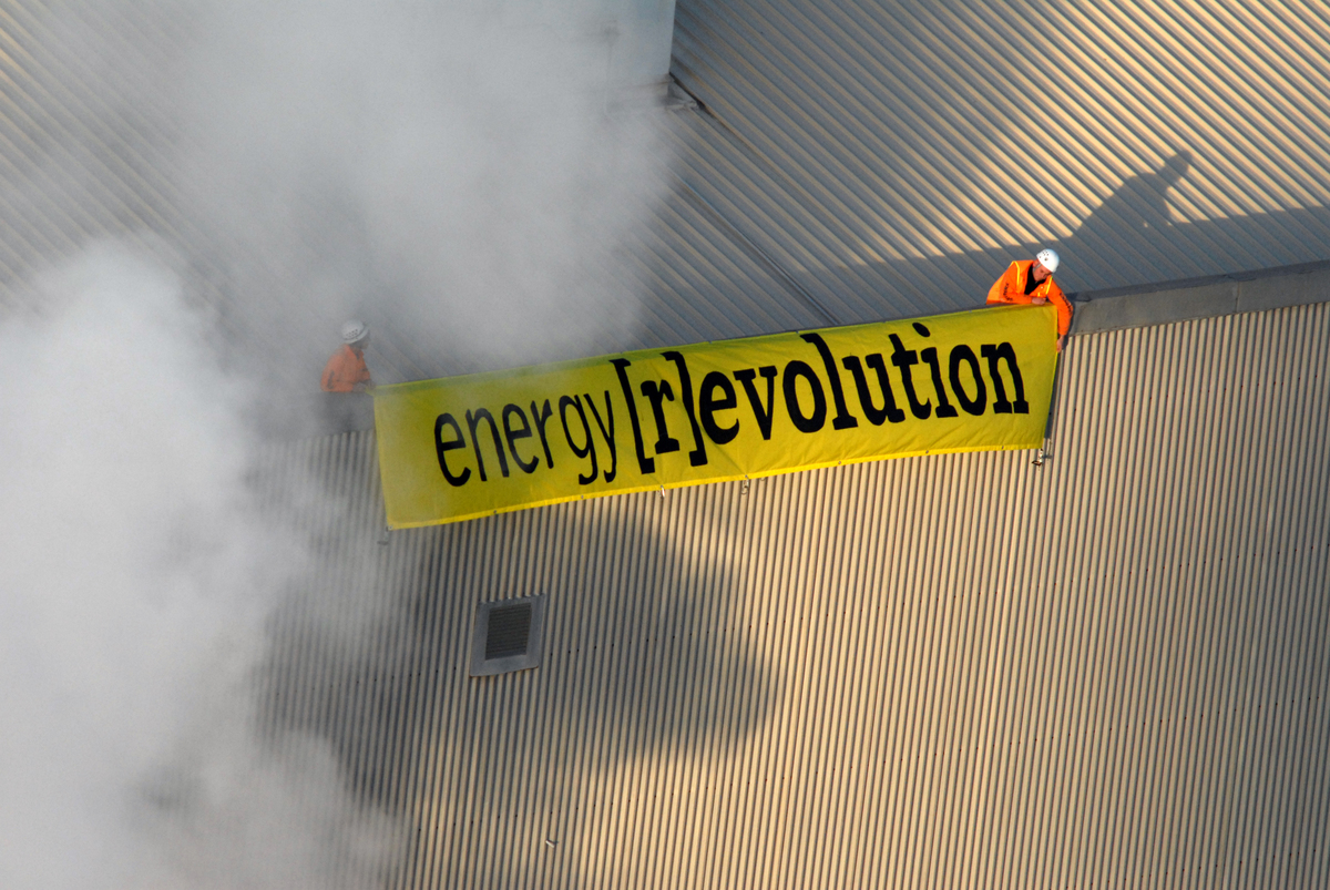 Two Greenpeace activists unfurl a banner reading "Energy [R]evolution" on the roof of the 37-year-old Swanbank B coal-fired plant. Four other Greenpeace activists scaled a 140-metre-high smokestack of the Swanbank coal-fired power station to call for Australia to be powered by renewable energy.
