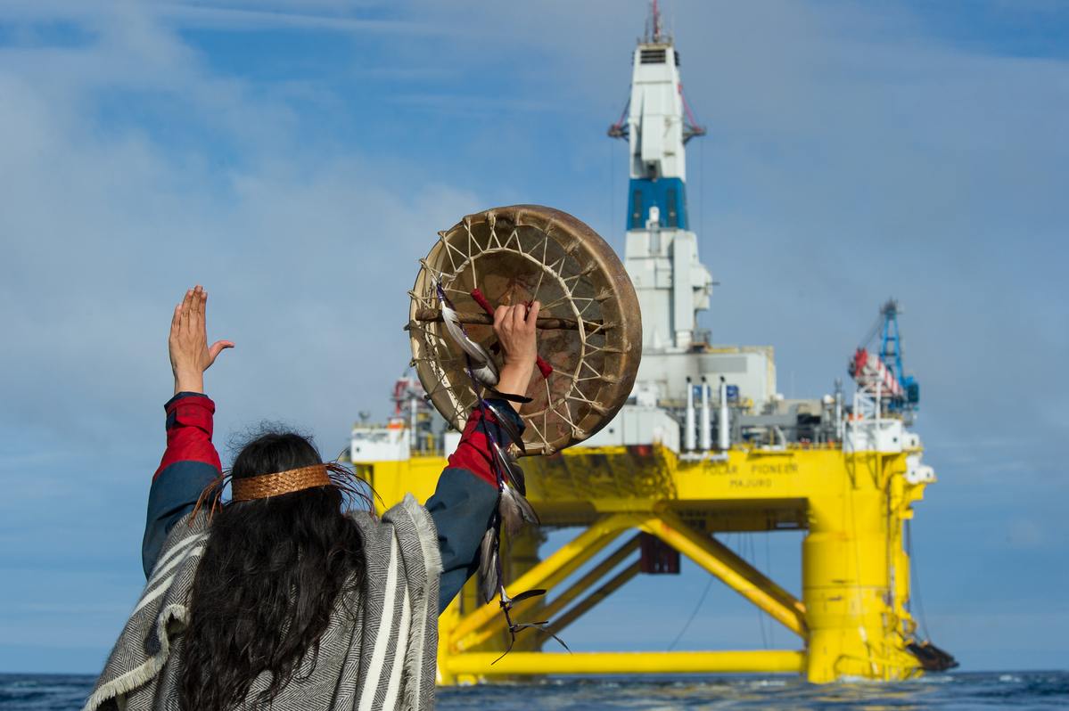 Audrey Siegl, a Musqueam woman from British Columbia, Canada, who is also a renowned public speaker, drummer and singer, stands in a Greenpeace rhib launched from the MY Esperanza holding her arms out in front her, defiantly signalling Shell's subcontracted drilling rig, the Polar Pioneer, to stop.