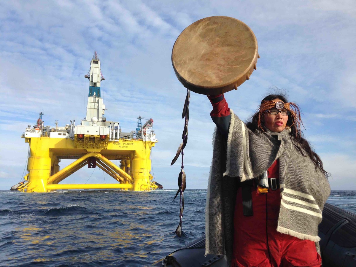 Audrey Siegl, a Musqueam woman from British Columbia, Canada, who is also a renowned public speaker, drummer and singer, stands in a Greenpeace rhib launched from the MY Esperanza, holding her arm out in front her, defiantly signalling Shell's subcontracted drilling rig, the Polar Pioneer, to stop.