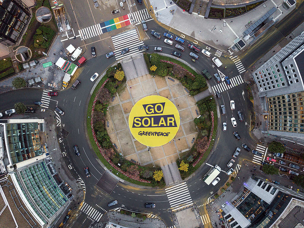 כיכר ומסביבה מכוניות ובאמצעה שלט צהוב גדול עליו כתוב ״ללכת על סולארי״