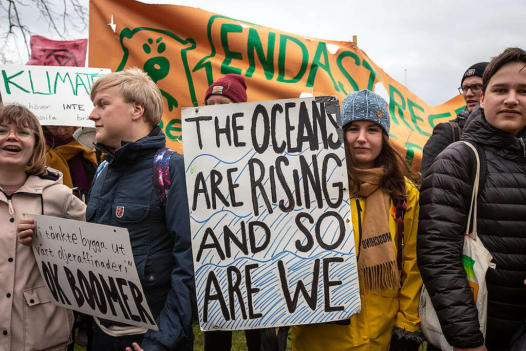 אישה במצעד למען האקלים עם שלט שכתוב עליו ״האוקיינוסים עולים, וגם אנחנו״. 