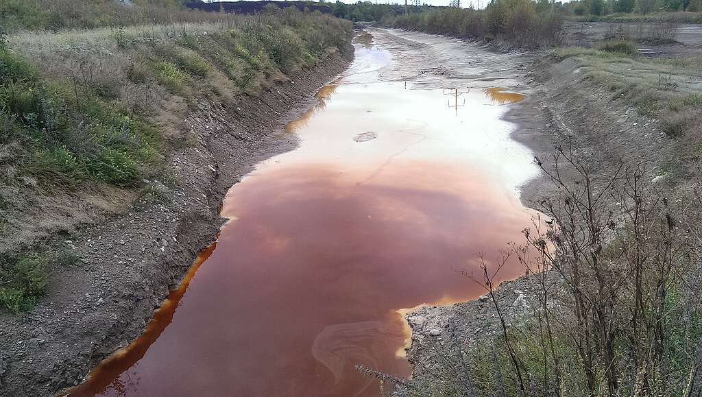 תעלת מים מזוהמים עם מים בצבע חלודה.