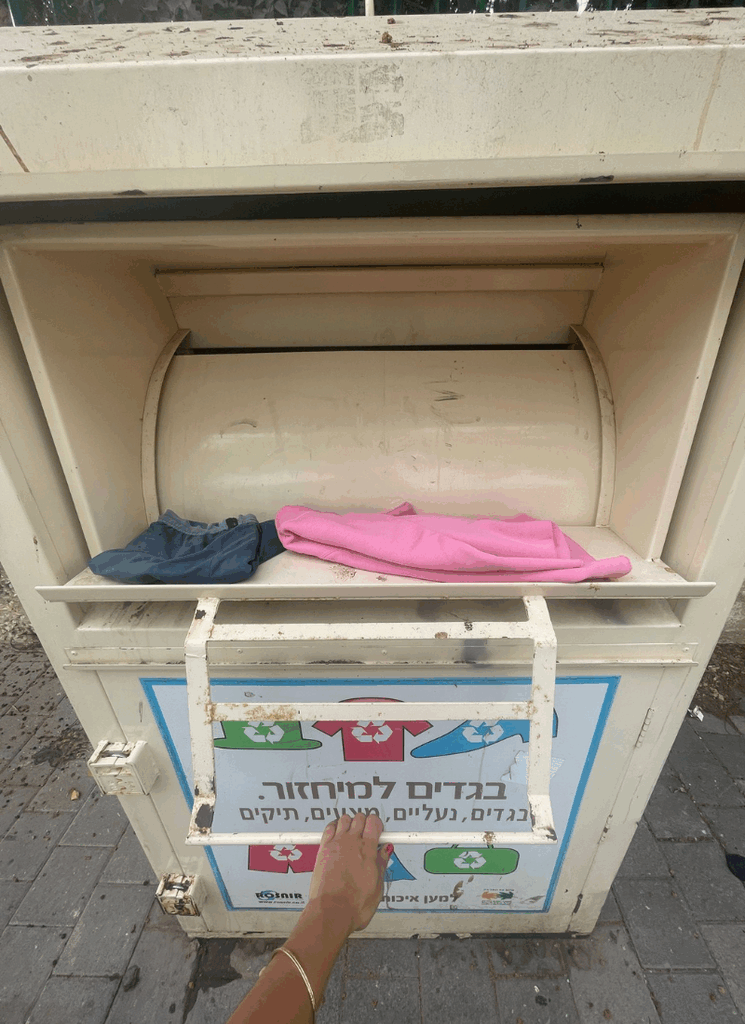 יד מכניסה שני בגדים משומשים לפח מיחזור טקסטיל.