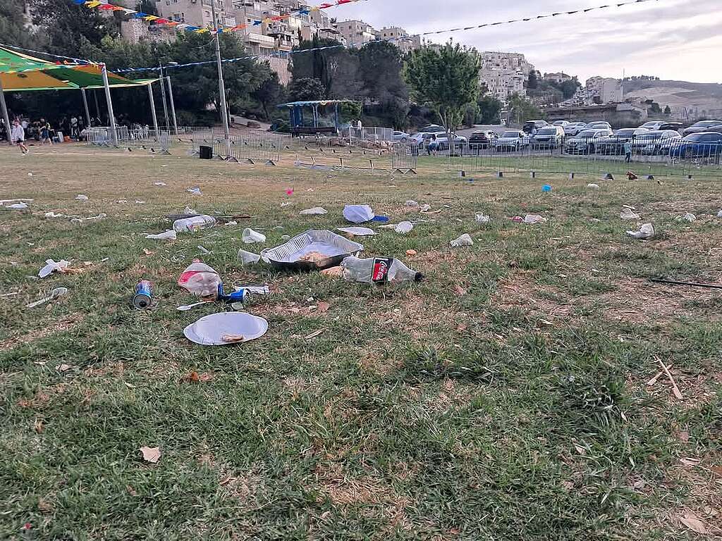 דשא בגן ציבורי בירושלים עם פסולת פלסטיק של כלים חד-פעמיים.