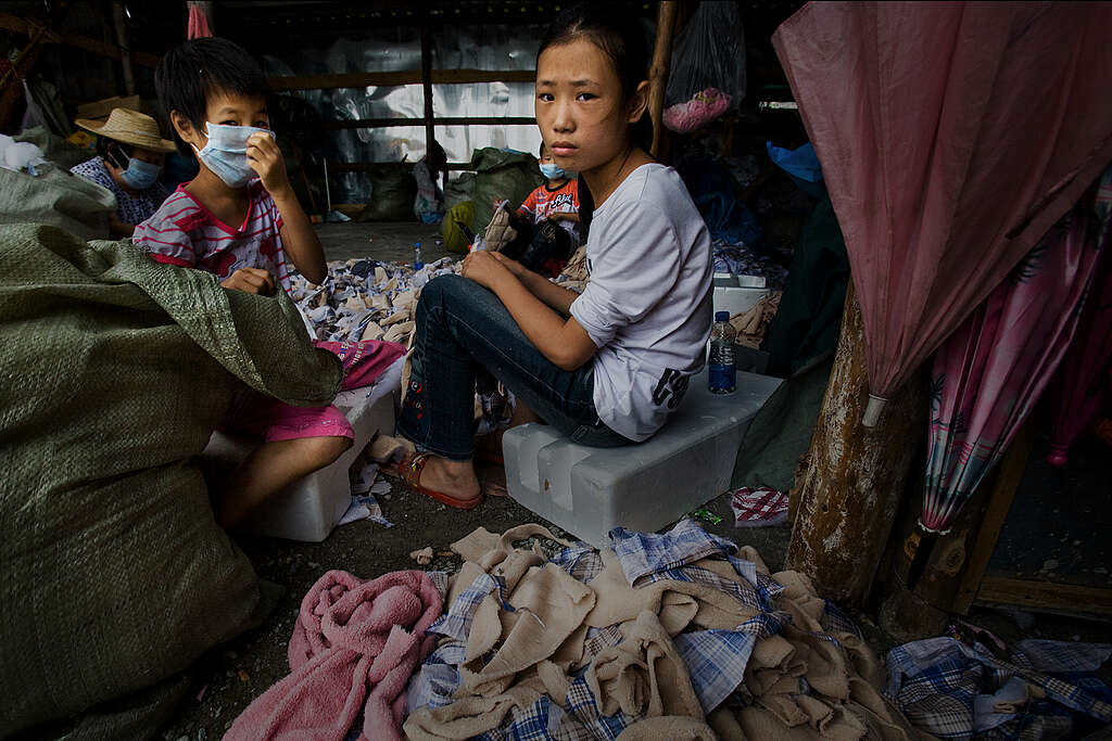 ילדה סינית מוקפת בבדים בבית מלאכה בסין