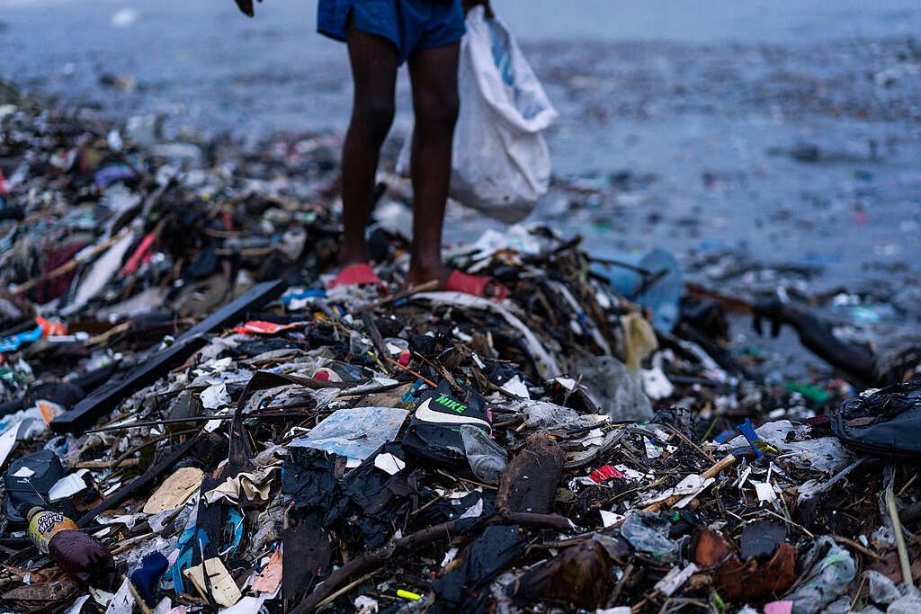 ילד אפריקאי עומד על פסולת טקסטיל שמזהמת את חוף הים בגאנה.