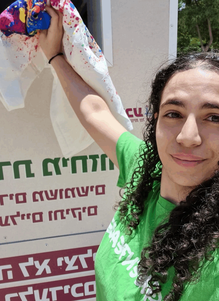 פעילת גרינפיס בחולצה ירוקה מכניסה בגד משומש לפח מיחזור. 