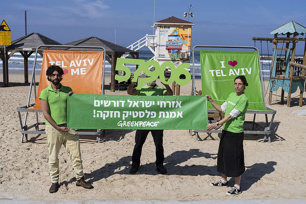 פעילי גרינפיס ישראל מחזיקים שלט ירוק ועליו כתוב ״אזרחי ישראל דורשים אמנת פלסטיק חזקה״ ומעל את המספר 57,906, כמספר החתימות של ישראלים על עצומת הפלסטיק של גרינפיס.