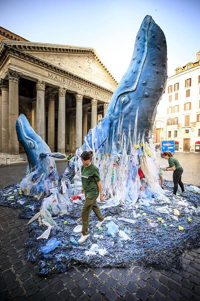 פעילי גרינפיס מכינים מיצב של לוויתנים יוצאים ממים מלאים פסולת פלסטיק, מול הקולוסיאום ברומא.