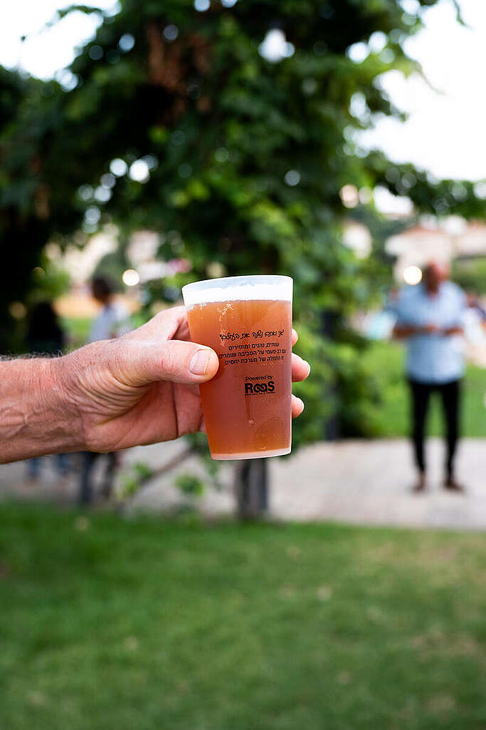 יד מחזיקה כוס פלסטיק רב-פעמית מלאה בבירה.