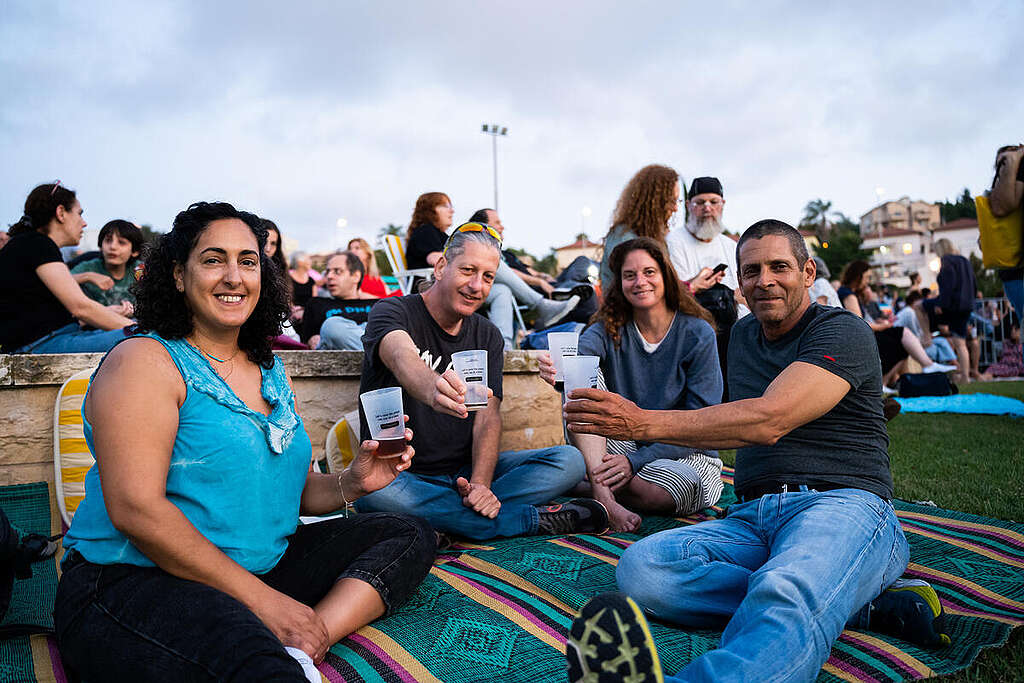 שני זוגות יושבים על מחצלת ומחזיקים כוסות בירה רב-פעמיות.