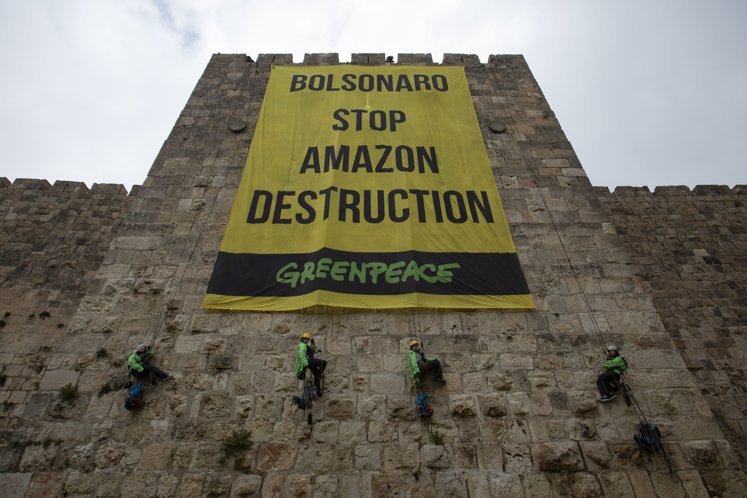Protest against President Bolsonaro in Jerusalem פעילי גרינפיס עושים סנפלינג על חומות ירושלים ופותחים כרזה ענקית בצבע צהוב הקוראת לבולסונארו לעצור את הרס האמזונס