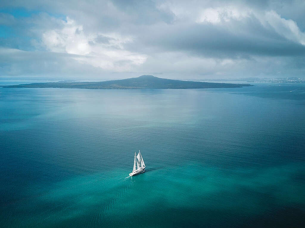 צילום רחפן של ספינה קטנה שטה בים בצבע טורקיז-כחול