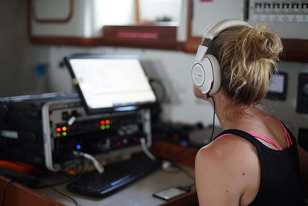 אישה יושבת עם אוזניות ומאזינה למכשיר האזנה ליונקים ימיים.