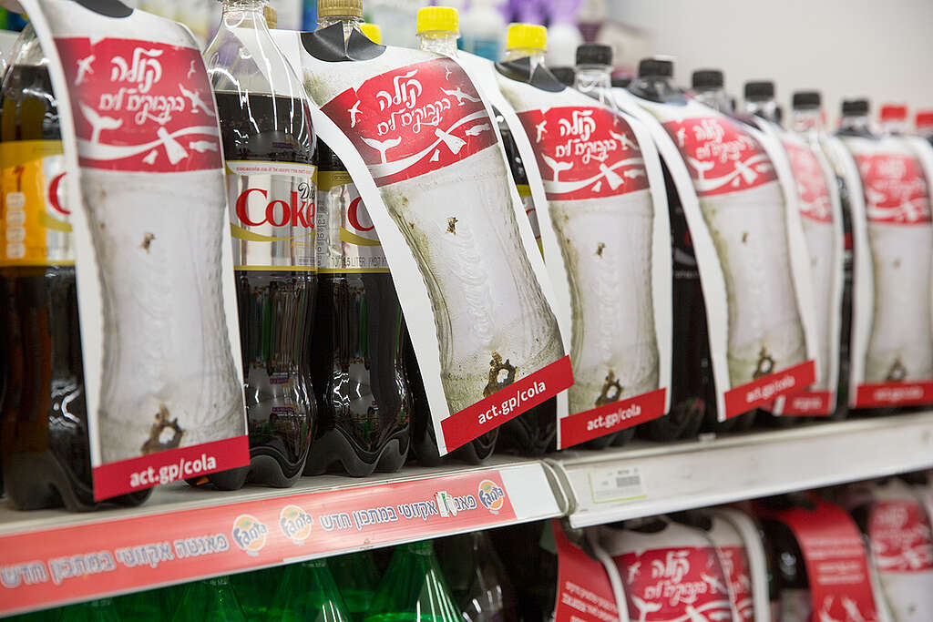 בקבוקי ליטר וחצי של קולה עם עטיפת בריסטול שמונחת עליהם ועליה כתוב ״קולה בקבוקים לים״