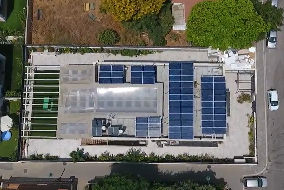 D3e8bc17 Nl 20261015 Solar Roof צילום אוויר של גג מבנה בנס ציונה מכוסה בפאנלים סולאריים