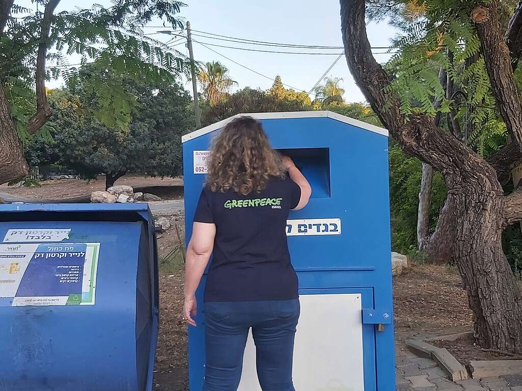 אישה לובשת חולצת Greenpeace זורקת בקבוק למחזור