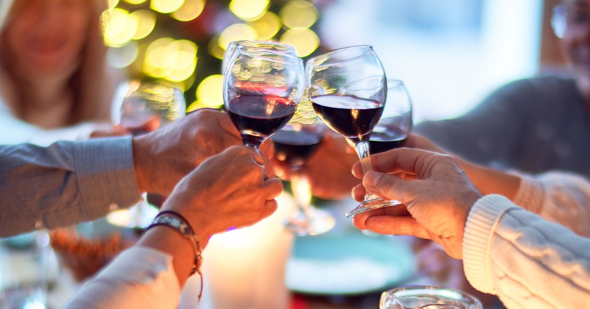 Una famiglia a tavola che brinda alzando calici di vino