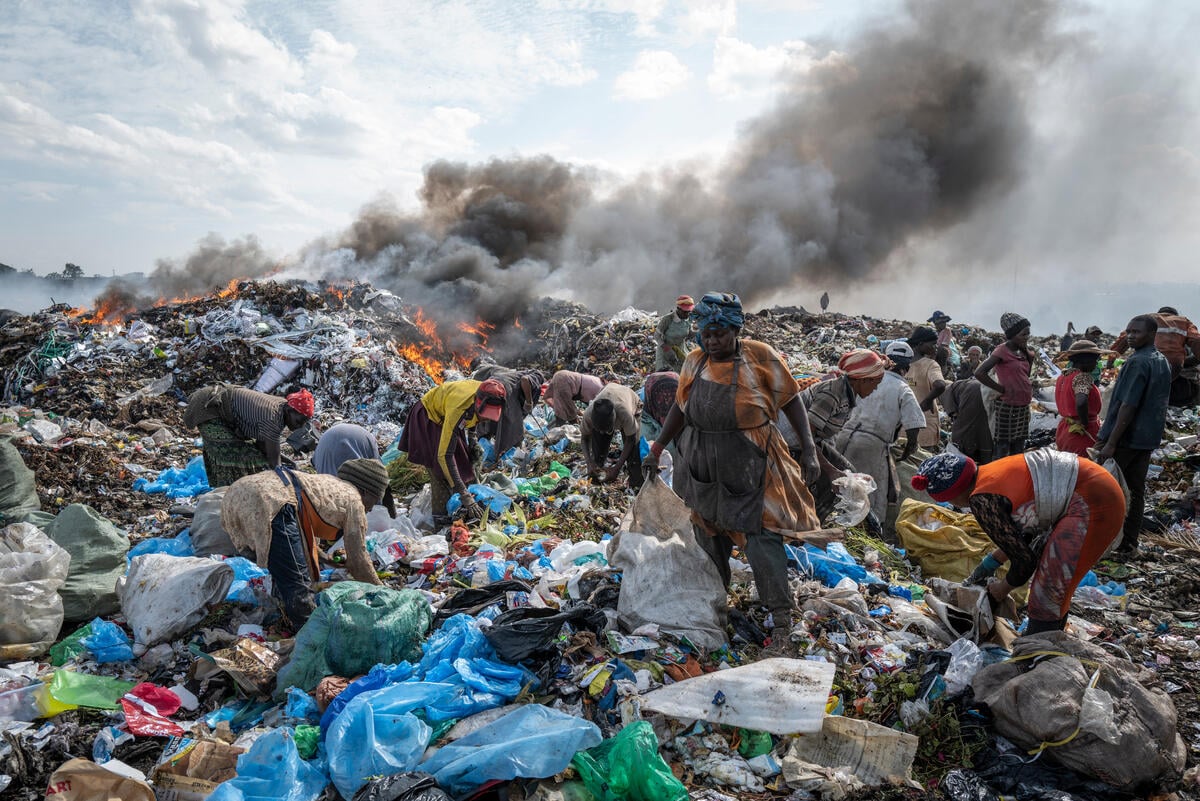 Uomini e donne in mezzo ai rifiuti tessili e plastici nella discarica di Dandora a Nairobi