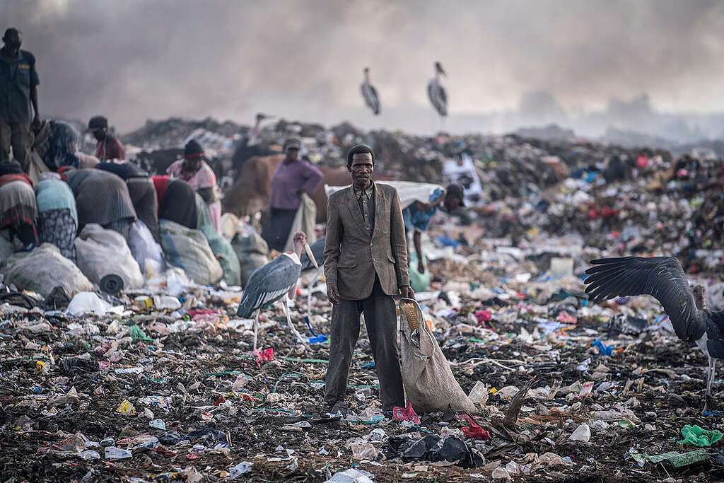 Un uomo in piedi su una distesa di rifiuti tessili nella discarica di Dandora, in Kenya