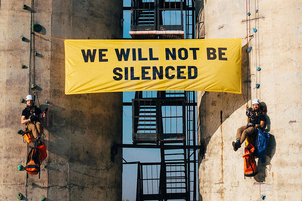 Attivisti di Greenpeace Polonia appesi su un edificio srotolano uno striscione con un messaggio per Energy Transfer: “Non saremo messi a tacere”. Attivisti di Greenpeace Polonia appesi su un edificio srotolano uno striscione con un messaggio per Energy Transfer: “Non saremo messi a tacere”.