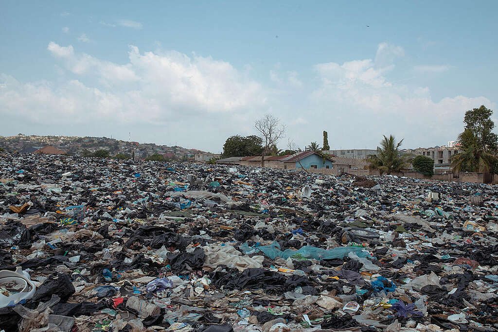 Una distesa di rifiuti tessili si estende a perdita d'occhio nella discarica. Sullo sfondo, alcune abitazioni. Una distesa di rifiuti tessili si estende a perdita d'occhio nella discarica. Sullo sfondo, alcune abitazioni.