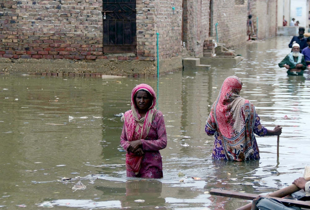 パキスタン、シンド州ハイデラバード。モンスーンの大雨で洪水が発生し、下水道が破壊された水の中を歩く人々。
