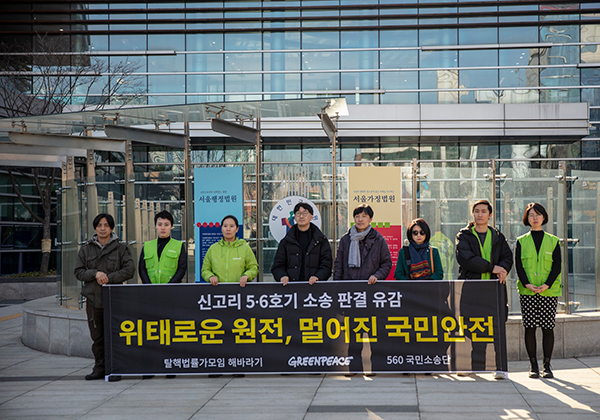 서울행정법원 앞에서 그린피스 활동가들과 560 소송단이 신고리 5,6호기 건설 허가 취소소송 사정 판결에 유감을 표하며 "위태로운 원전, 멀어진 국민안전"이라고 쓰인 배너를 들고 있다. 