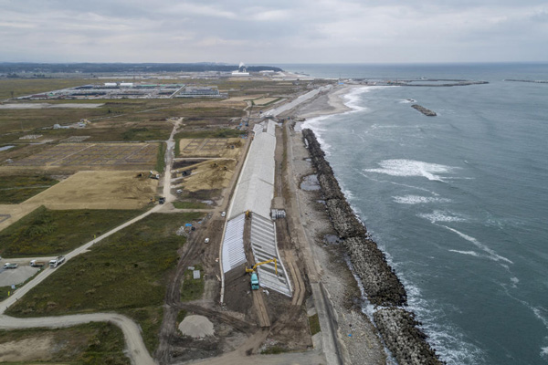 바닷물 유입을 막기 위해 콘크리트 구조물이 태평양 해안을 따라 새로 세워졌다. 멀리 집들이 보이는 마을은 후쿠시마 제1원전에서 북쪽 10km가량 떨어진 나미에 지역이다. 수증기가 나오는 건물은 핵쓰레기 소각공장이다