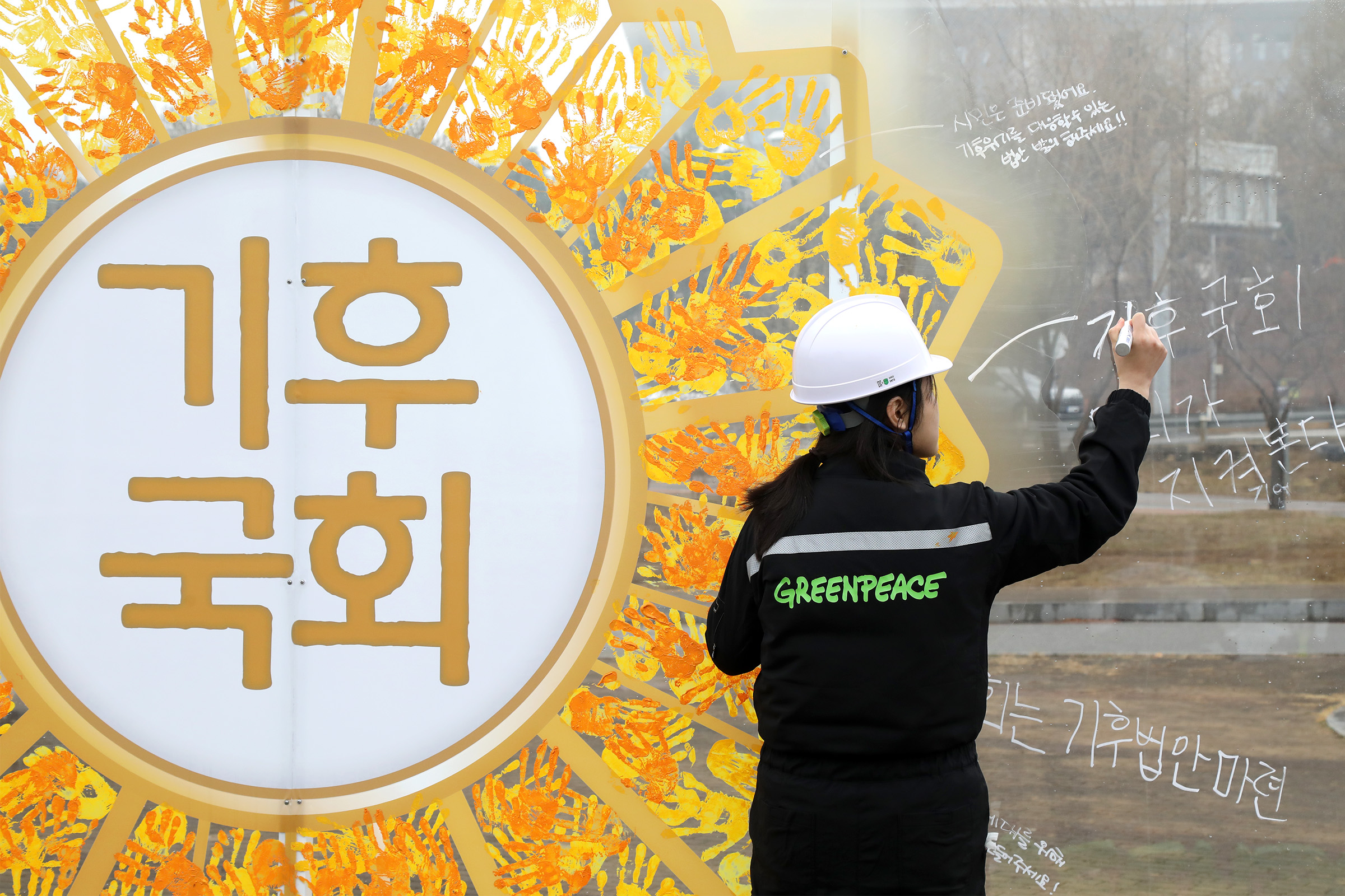 시민들이 기후국회를 요구하는 메시지를 투명벽면에 적고 있다.