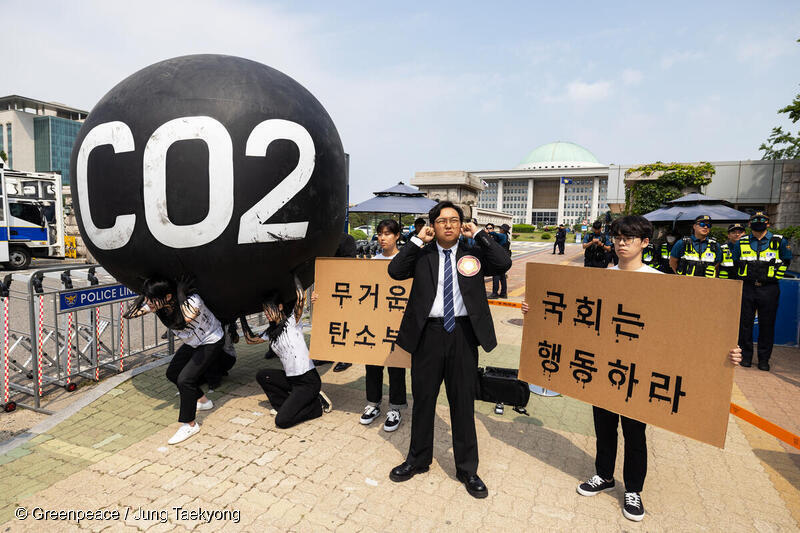 청년기후활동가들과 그린피스가 국회 앞에서 탄소의 짐 퍼포먼스를 펼치고 있는 모습. 국회의원 모습을 한 청년활동가가 청년들의 목소리를 외면하는 자세를 취하고 있다.