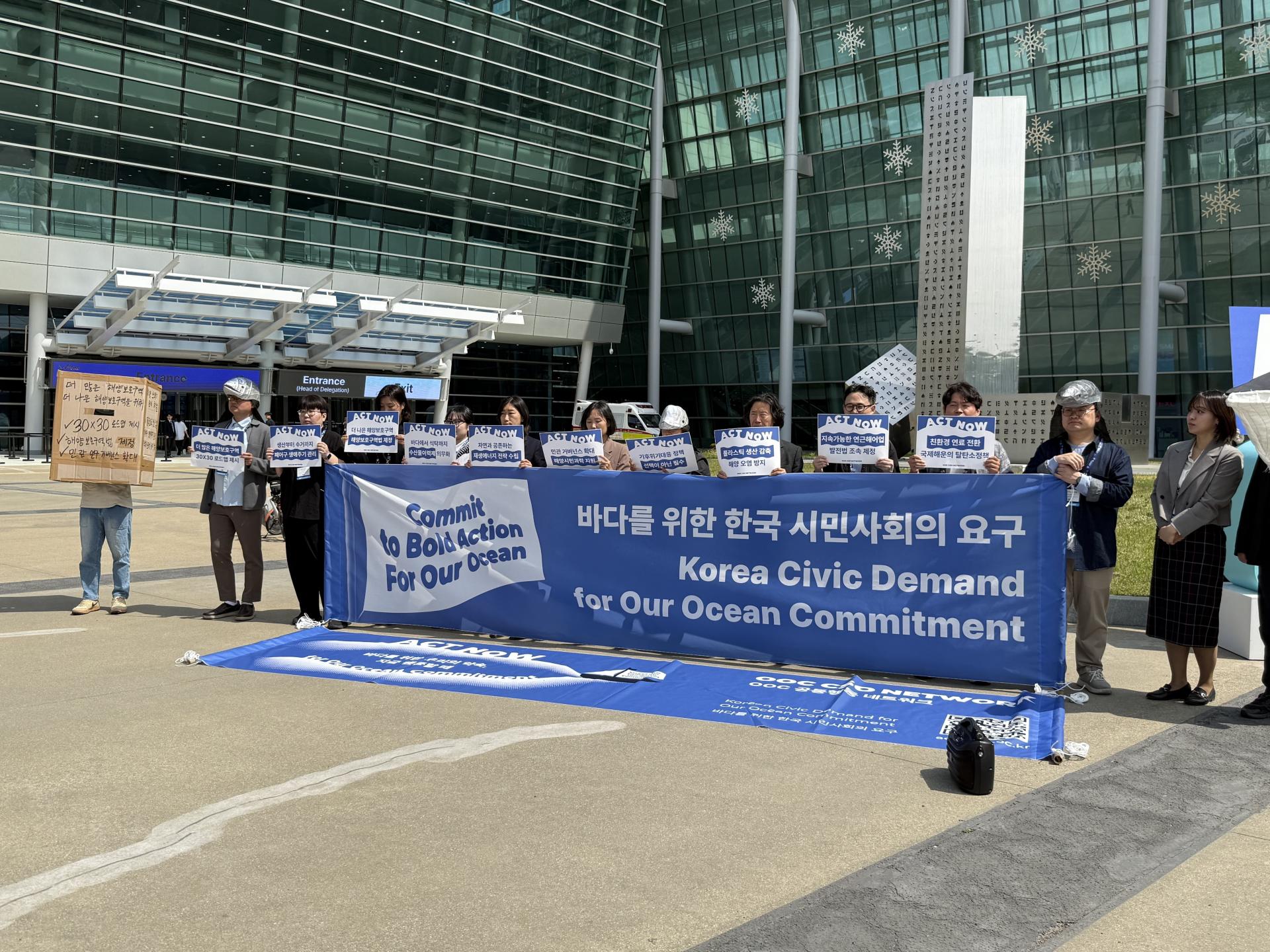 제10차 OOC 콘퍼런스 장소에서 시민사회연대체가 배너를 들고있다.