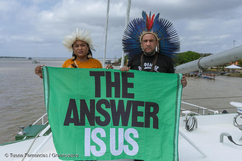 기후총회가 열리는 브라질 벨렘에서 선주민 지도자가 그린피스 레인보우호 위에서 아마존 보호를 촉구하는 배너를 들고 있다.