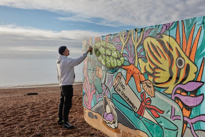예술가 리히트가 영국 이스트 서식스 주 바닷가에서 벽화를 그리고있다.