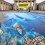 브란덴부르크 문 앞 그려진 해양 벽화를 배경으로 그린피스 액티비스트가 배너를 들고있다.