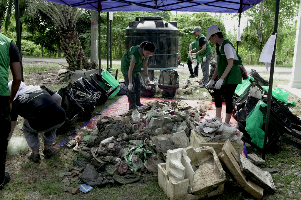 Greenpeace Malaysia volunteers diligently sorting through a large pile of garbage collected from the Klang River. 