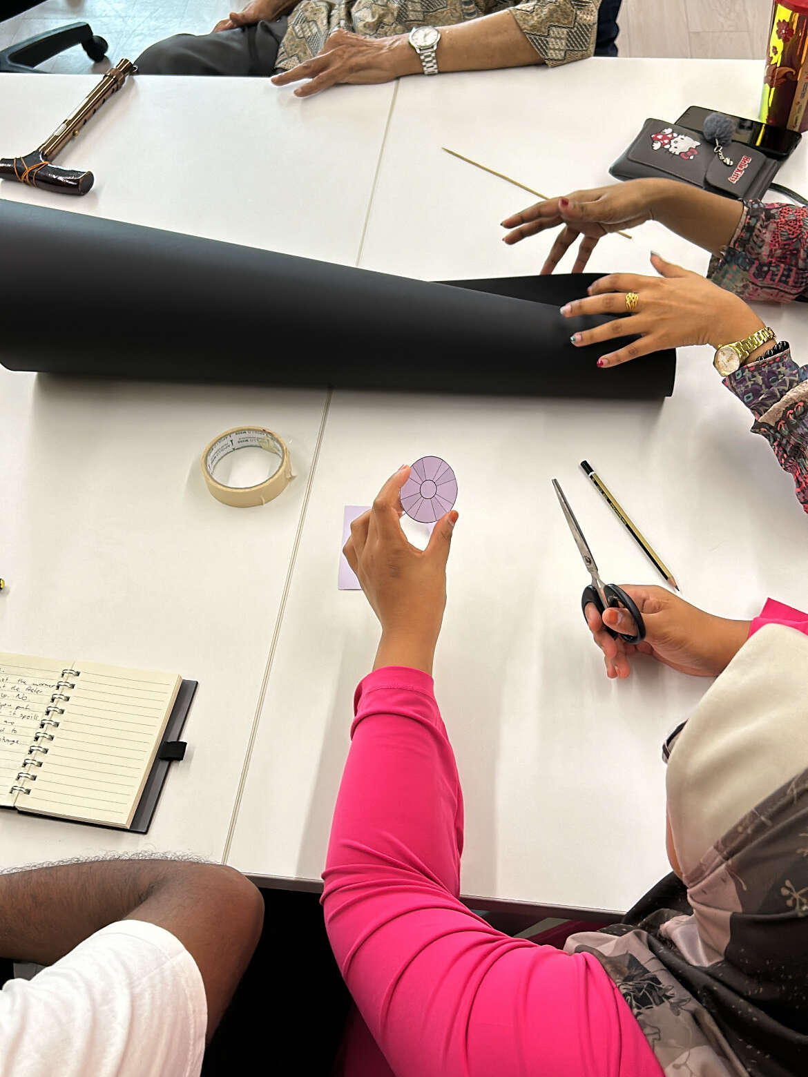 Several people gather at a table, engaged in building a DIY power generator together.