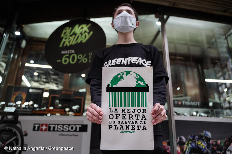 Activista de Greenpeace en protesta, sosteniendo un cartel que dice: “La mejor oferta es salvar el planeta”