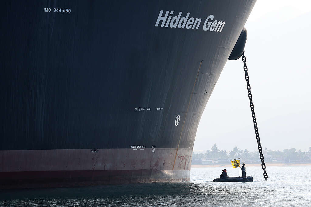 Activistas de Greenpeace en una balsa junto al Hidden Gem, sosteniendo una bandera con el mensaje "Stop deep sea mining".