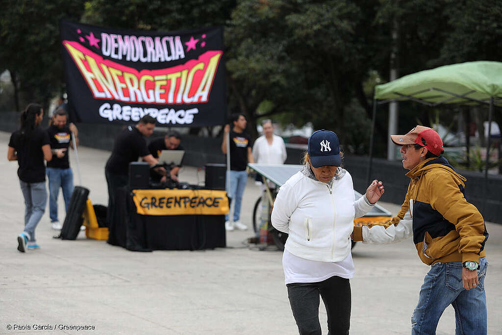 Activistas de Greenpeace México transportando un panel solar y una bandera que dice 'democracia energética', marchando por las calles de CDMX para apoyar el acceso a energías renovables.