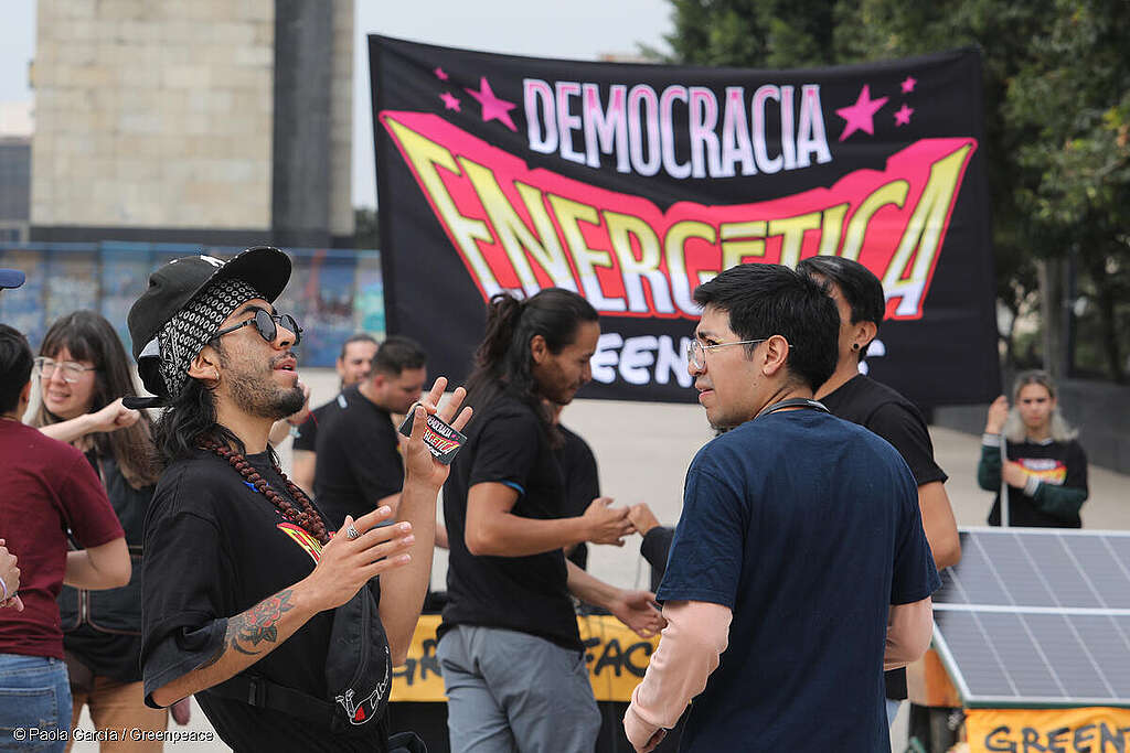 Activistas de Greenpeace México sosteniendo un panel solar y una bandera que dice 'democracia energética', mientras caminan por la CDMX, destacando soluciones energéticas sostenibles.