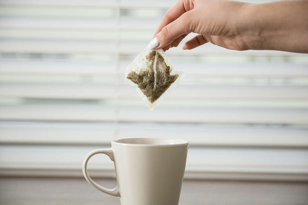 Mano sosteniendo una bolsita de té sobre una taza. Mano sosteniendo una bolsita de té sobre una taza.