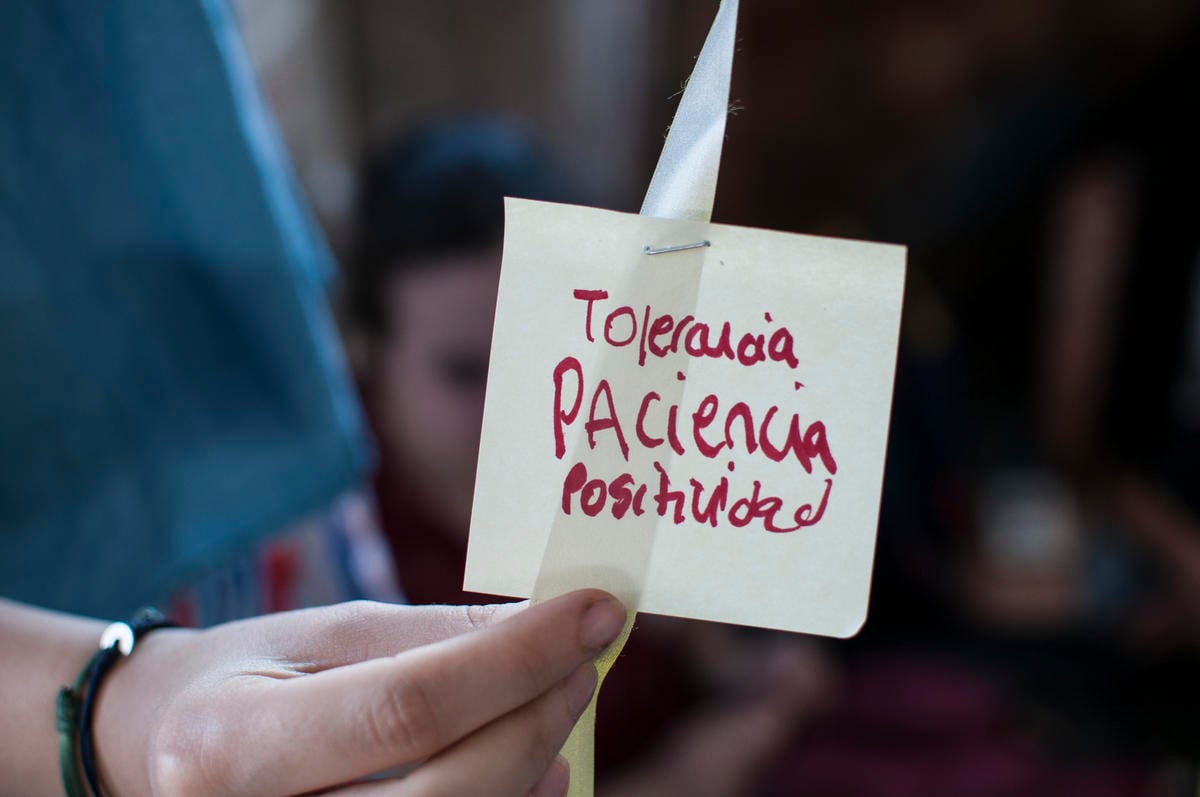 Voluntarios sostienen un post-it con las palabras "tolerancia, paciencia, positividad", destacando valores clave para el activismo.
