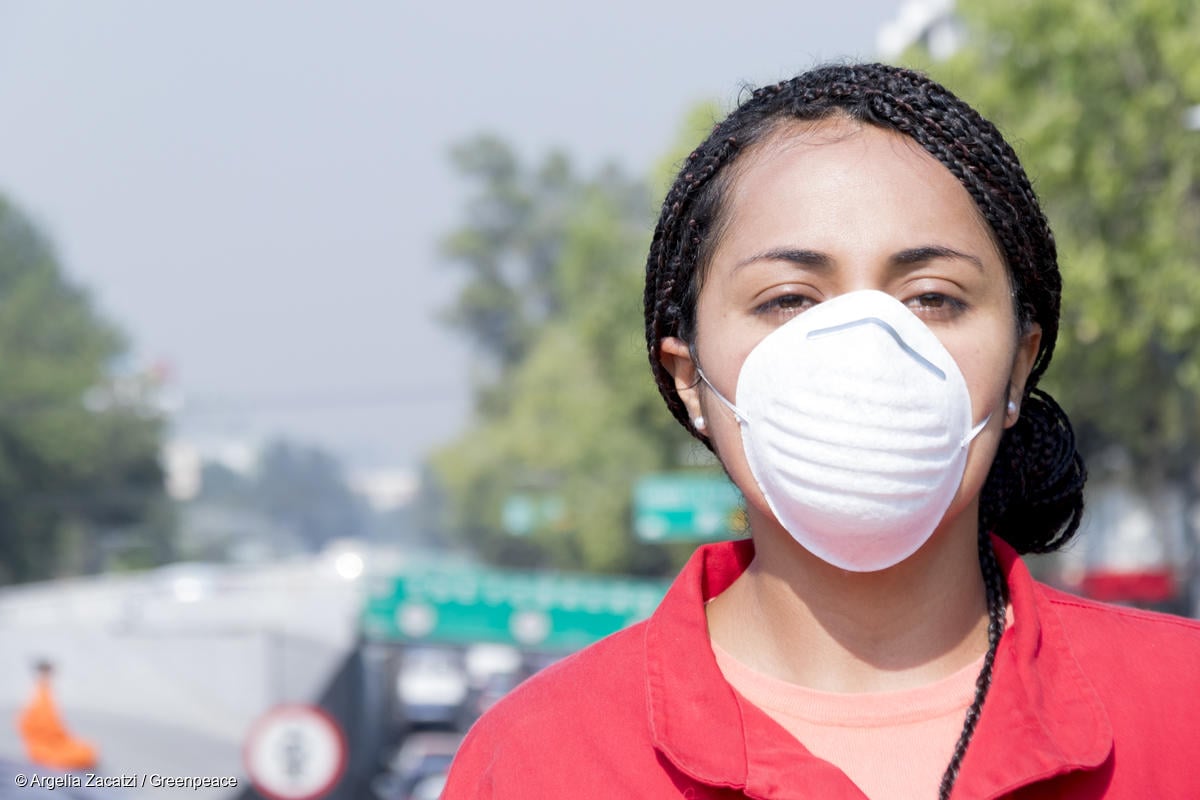 Activista de Greenpeace México con cubrebocas en protesta por la mala calidad del aire y la falta de respuesta de COFEPRIS ante la crisis ambiental.