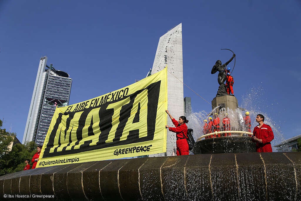 Activistas colocando una mascarilla y un tanque de oxígeno en la estatua de Diana Cazadora en la Ciudad de México con el mensaje “El aire en México MATA” para exigir aire limpio.